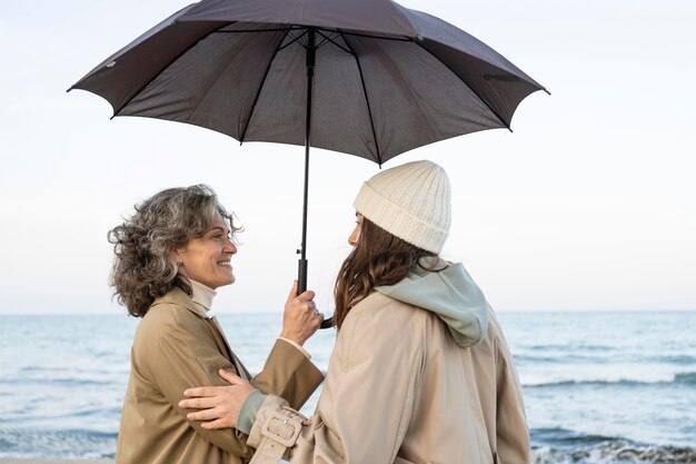 Мать и дочь разделяют нежный момент на пляже под зонтиком