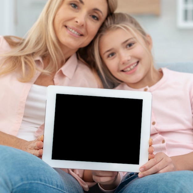 Free photo mother and daughter showing a mock up frame