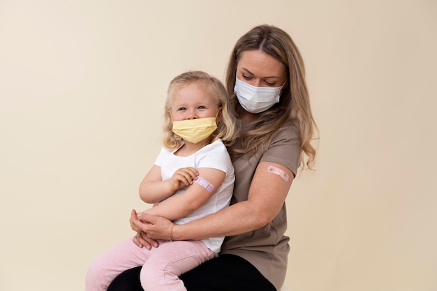 Free photo mother and daughter showing sticker on arm after getting a vaccine