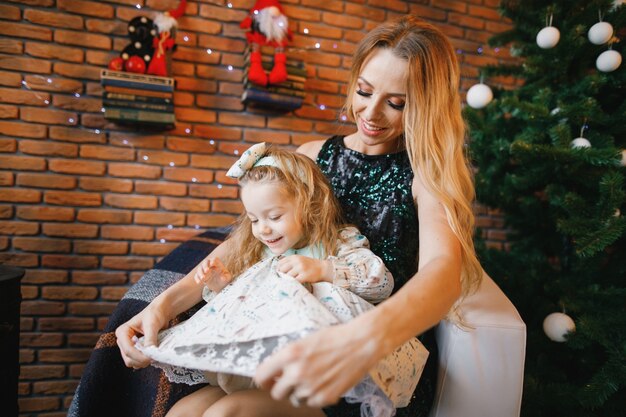 mother and daughter sitting by the christmas tree