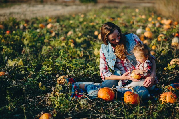 Mother and daughter sitting in a field of pumpkins