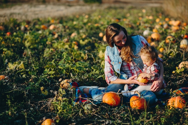 Mother and daughter sitting in a field of pumpkins