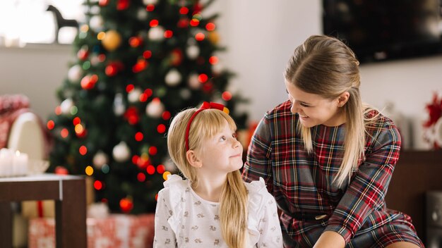 Mother and daughter sitting in front of christmas tree