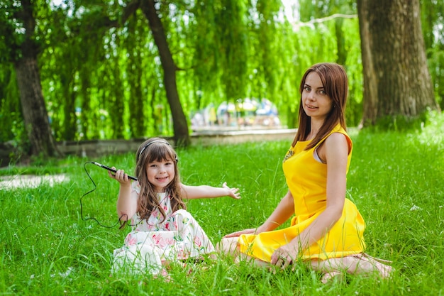 Free photo mother and daughter sitting on the lawn