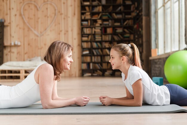 Foto gratuita madre e figlia che si siedono sulla stuoia che se lo esamina