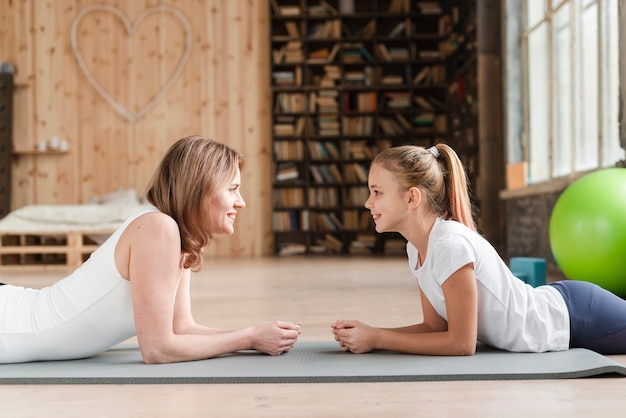 Mother and daughter sitting on mat looking at each other