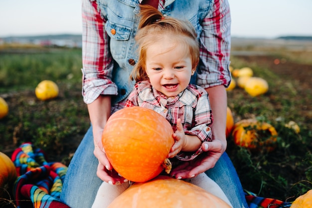 Free photo mother and daughter sitting on pumpkins