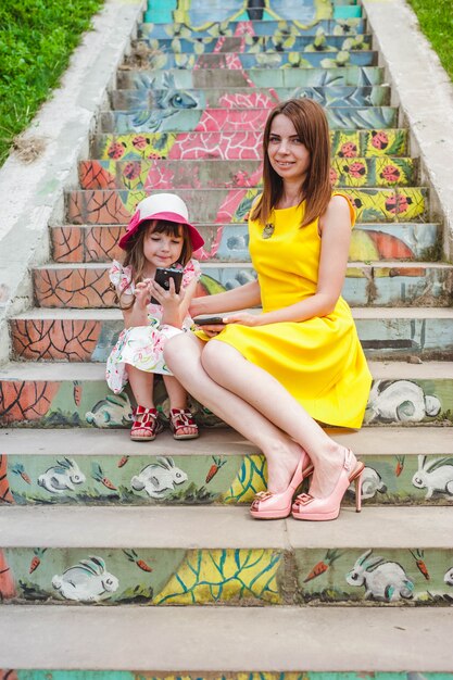 Mother and daughter sitting on stairs and girl with a phone