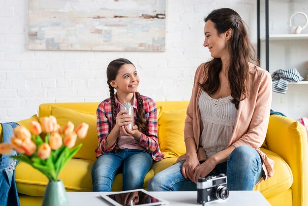 Mother and daughter sitting on yellow couch