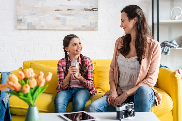 Mother and daughter sitting on yellow couch