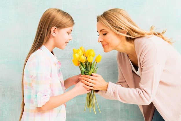 Mother and daughter smelling bouquet of flowers