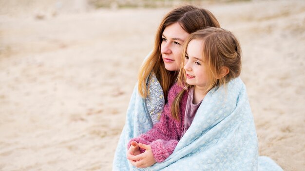 Free photo mother and daughter snuggling outdoors