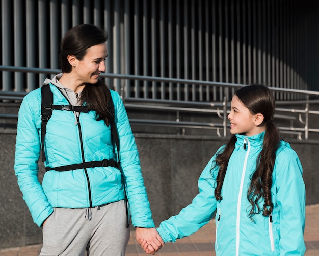 Mother and daughter in sportswear holding hands