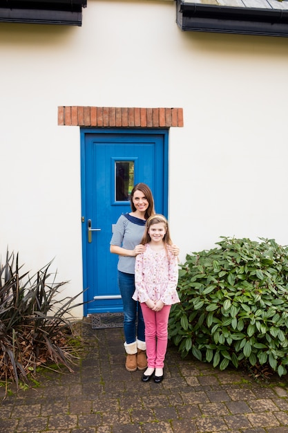 Free photo mother and daughter standing near house