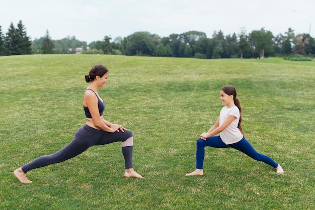 Free photo mother and daughter stretching outdoors