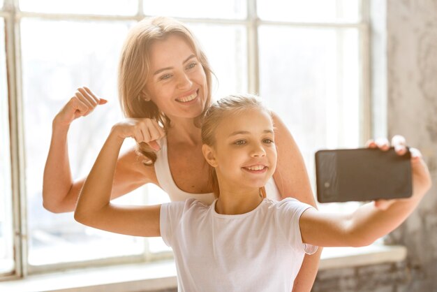 Mother and daughter taking selfie flexing arm muscles