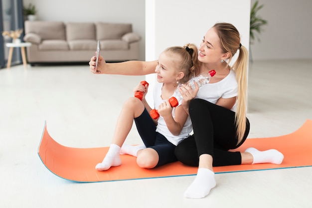 Free photo mother and daughter taking selfie while holding weights