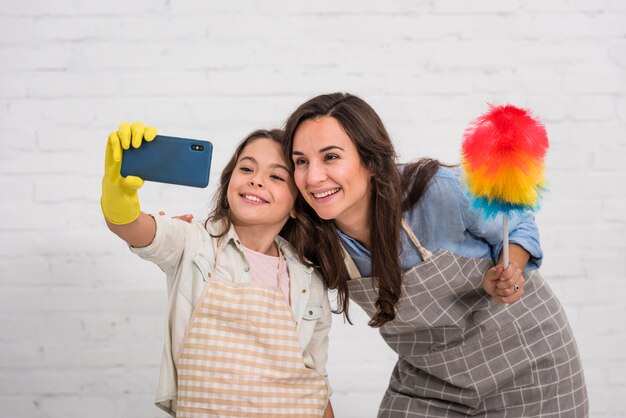 Mother and daughter taking a selfie with cleaning objects