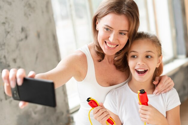 Mother and daughter taking selfie with jump rope