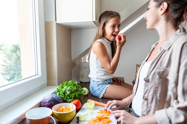 Free photo mother and daughter together in kitchen