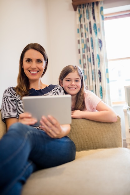 Mother and daughter using digital tablet in living room