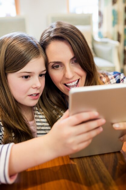 Mother and daughter using digital tablet in living room