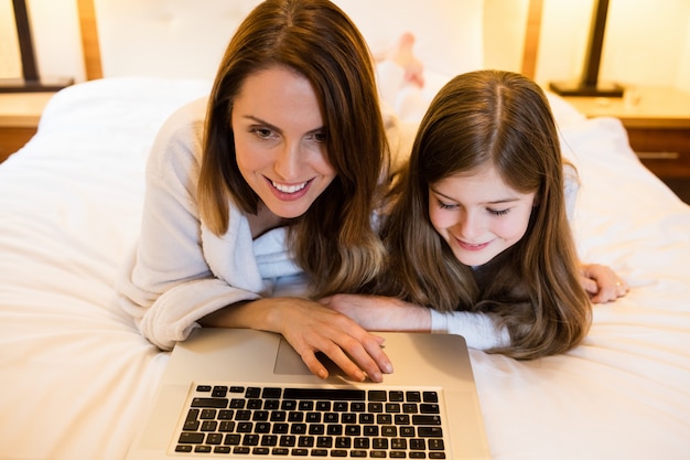 Madre e figlia con laptop in camera da letto