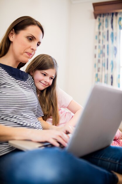 Mother and daughter using laptop in living room