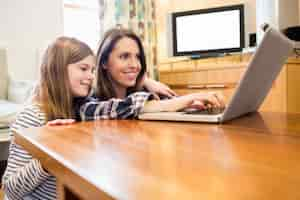 Free photo mother and daughter using laptop in living room