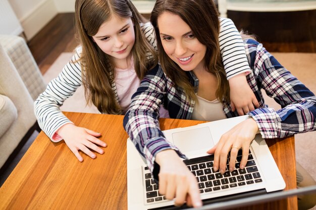 Mother and daughter using laptop in living room