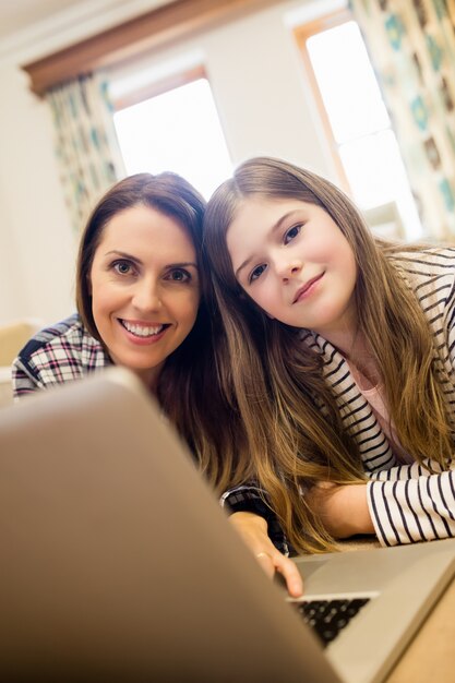 Mother and daughter using laptop in living room