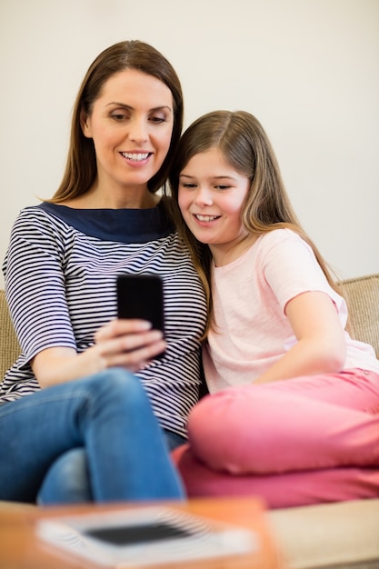 Free photo mother and daughter using mobile in living room