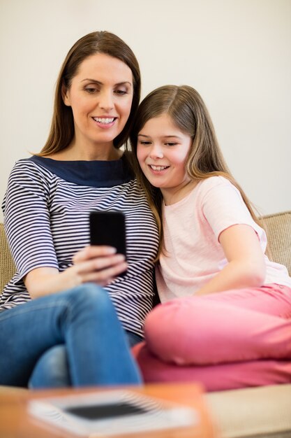 Mother and daughter using mobile in living room