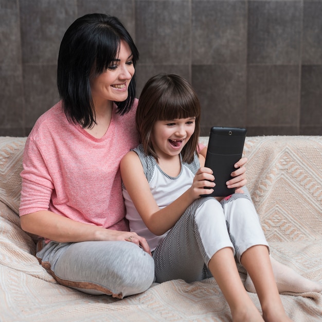 Mother and daughter using tablet on couch 