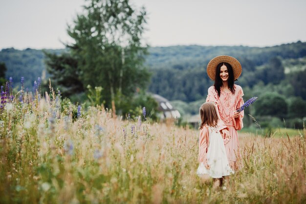 Mother and daughter walk on the green field 