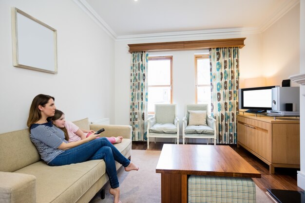 Mother and daughter watching tv in living room