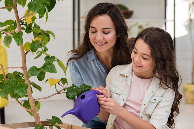 Mother and daughter watering the plant together