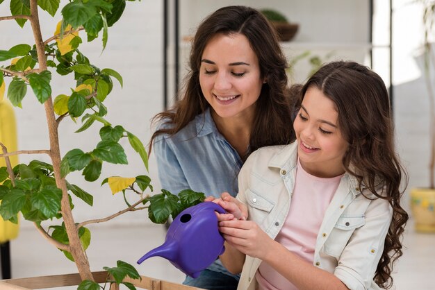 母と娘が一緒に植物に水をまく