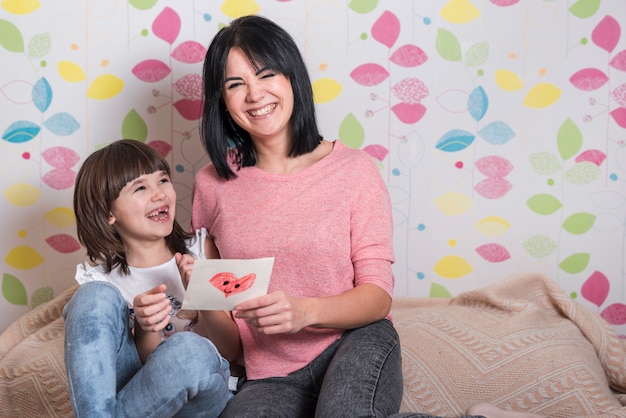 Mother and daughter with greeting card laughing