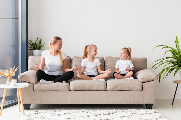 Mother and daughters exercising at home on couch