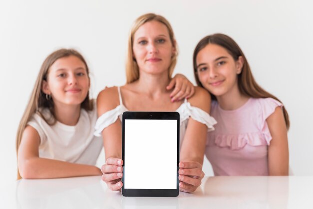 Mother and daughters holding tablet with blank screen 