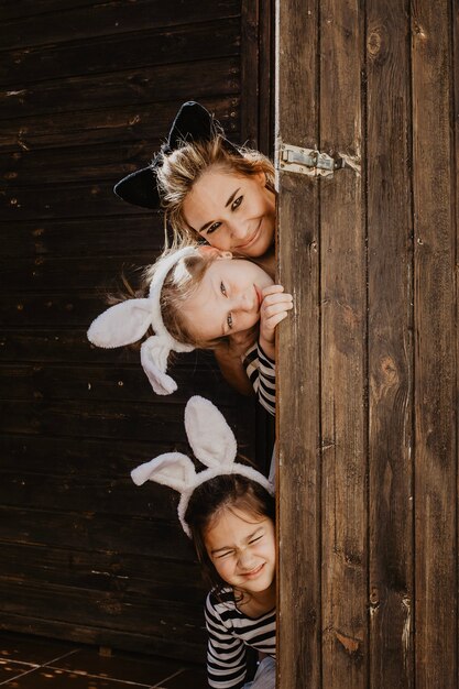 Mother and daughters peeking from behind door