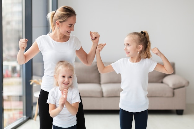 Mother and daughters showing off they biceps at home