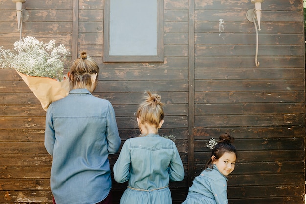 Free photo mother and daughters with flowers near shed