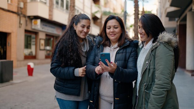 Mother and daugthers using smartphone standing together at street