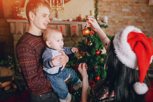 Mother distracting the baby with a christmas ornament while the father holds it in his arms