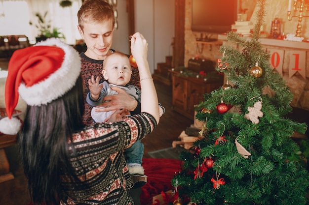 Mother distracting the baby with a christmas ornament while the father holds it in his arms