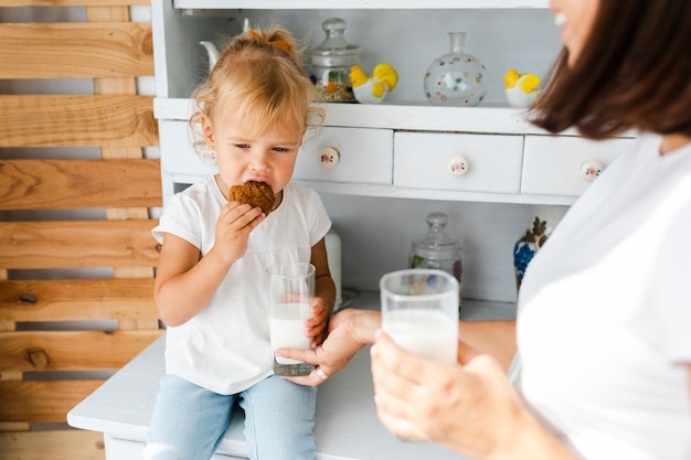 Foto gratuita latte alimentare e figlia della madre che mangiano i biscotti