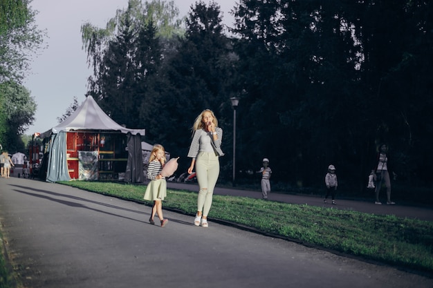 Mother eating an ice cream and her daughter pink cloud while walking