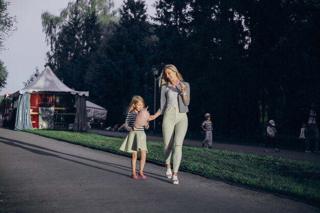 Mother eating an ice cream and her daughter pink cloud while walking